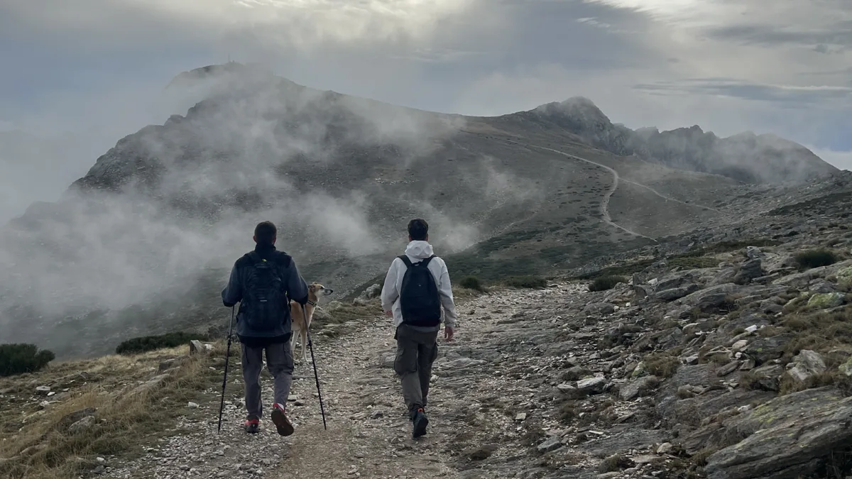 Zwei Wandernde mit Stöcken und großen Rucksäcken in den Bergen